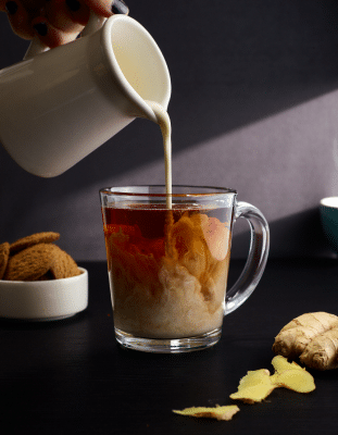 Milk being poured into a glass coffee mug